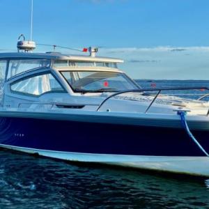 A well-equipped Nimbus W9 buttoned up against the Maine weather with full side curtains and an electrically powered sunroof. The mooring bridle takes advantage of both cleats on the bow. The electric anchor windlass can be operated with a remote control from anywhere on the boat; the remote also can run the bow thruster. The touches of orange are wind vanes on accessory whirligigs meant to deter gulls and cormorants. A well-equipped Nimbus W9 buttoned up against the Maine weather with full side curtains and an electrically powered sunroof. The mooring bridle takes advantage of both cleats on the bow. The electric anchor windlass can be operated with a remote control from anywhere on the boat; the remote also can run the bow thruster. The touches of orange are wind vanes on accessory whirligigs meant to deter gulls and cormorants.
