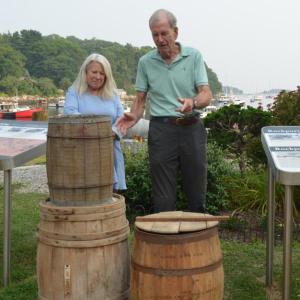 Camden-Rockport Historical Society President Susan Reider and Charlton Ames, president of Legacy Rockport, stand next to old caskets that were once filled with locally manufactured lime and carried to large harbors along the Eastern Seaboard to be used in making mortar and plaster in the building of American cities. (photo by Lynda Clancy) c
