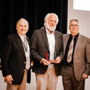 (Photo courtesy Knox Clinic) Three men. Man in middle holds award.