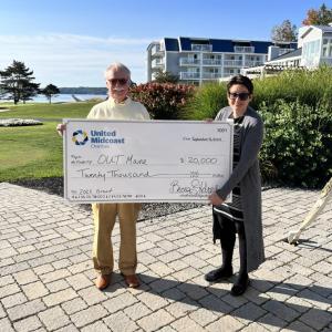 Development Director Rachel Albury (right) receives a $20,000 grant award from United Midcoast Charities on behalf of OUT Maine. (Photo courtesy OUT Maine) Man and woman pose with gigantic check