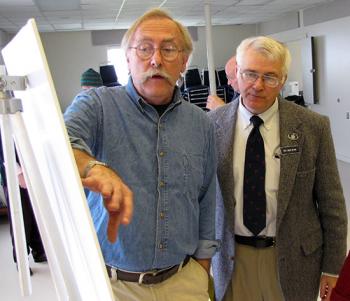 Stephen Miller, executive director of the Islesboro Islands Land Trust, left, gestures to a map of upper Penobscot Bay as Rep. Mick Devin looks on. (Photo by Tom Groening)